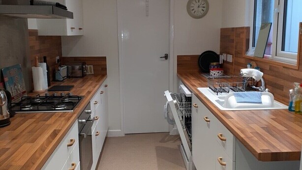 A modern kitchen with wooden countertops, white cabinets, a built-in dishwasher, and a window with a view. - Family holiday home near both sea front and town (Yarmouth)