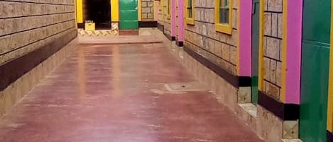 A corridor with a tiled floor and walls painted in pink, green, and yellow.