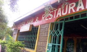 A building with a sign that reads "Manchester Bar & Restaurant" and another sign for "Manchester Club, The Theatre of Dreams." - Manchaster Bar Restaurant (Makindu)