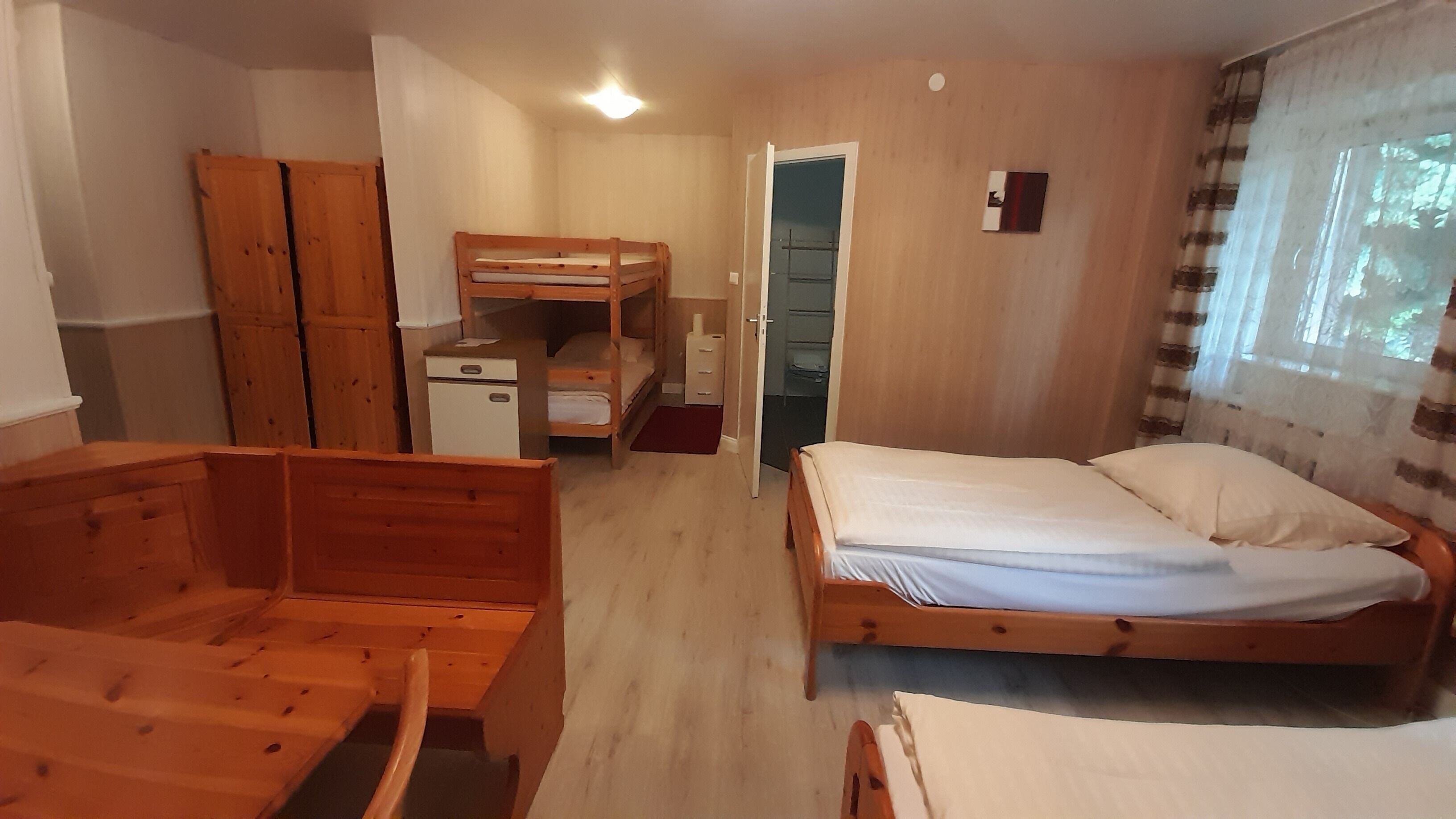Ein Zimmer mit Etagenbett, Schreibtisch, Stuhl, kleinem Schrank und Kleiderschrank.
