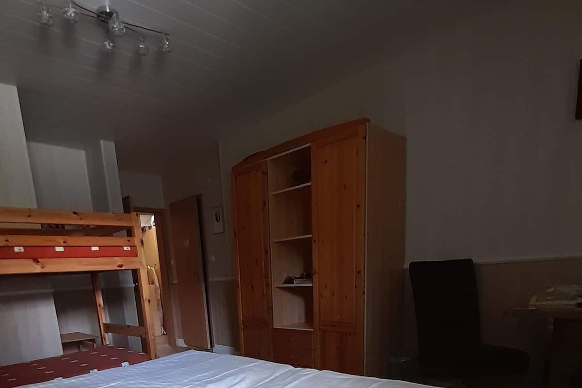 Ein Zimmer mit einem großen Bett, einem Holzschrank und einem Etagenbett.