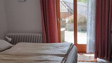 Ein Schlafzimmer mit Bett, Heizkörper, blauem Teppich und Blick nach draußen.