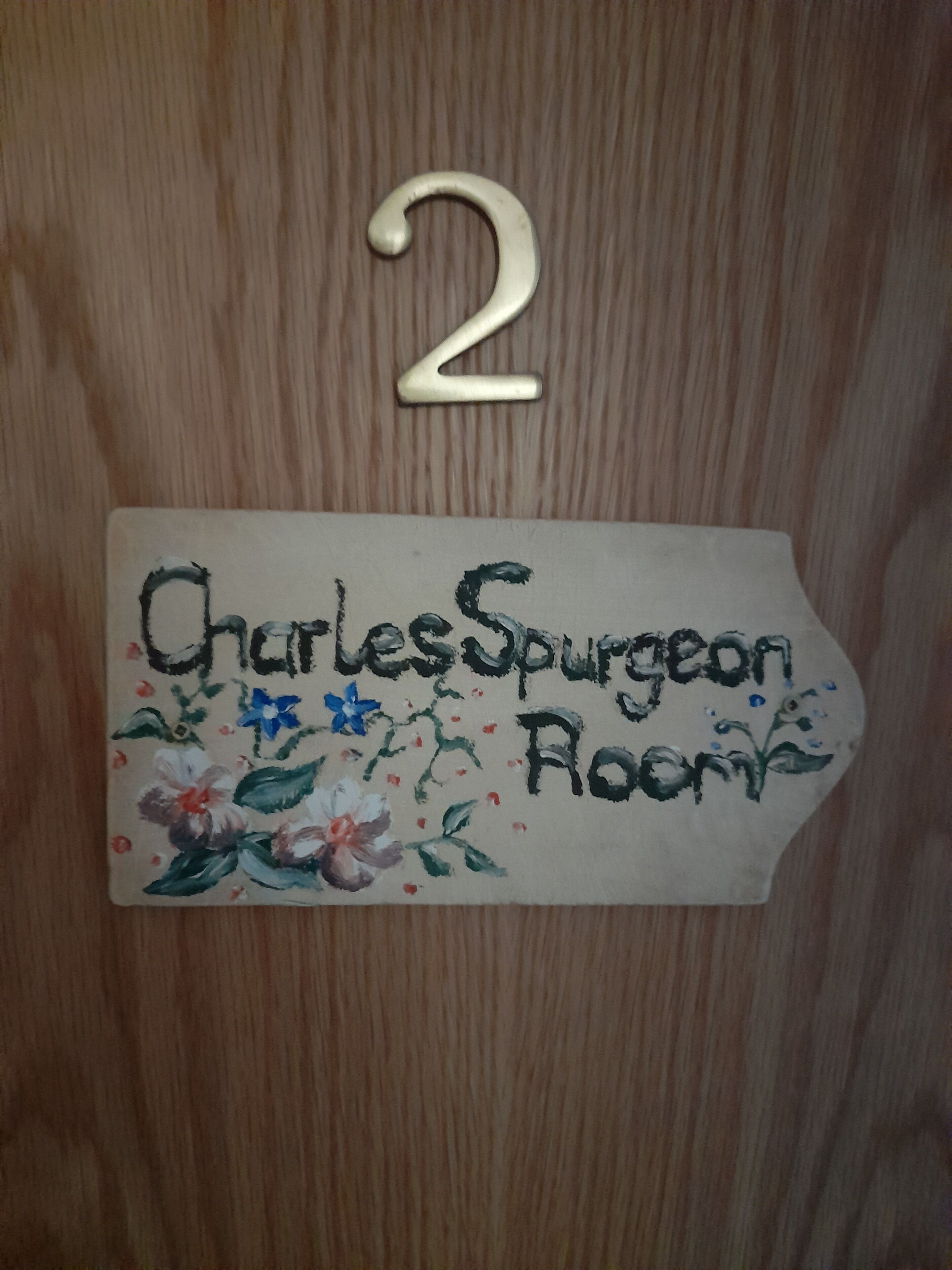 A wooden door with a sign indicating "Charles Spurgeon Room" and the number "2" above it.