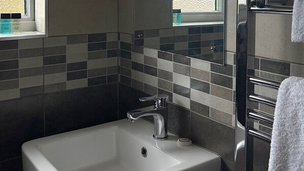 A bathroom with a white sink, chrome faucet, and a tiled backsplash.