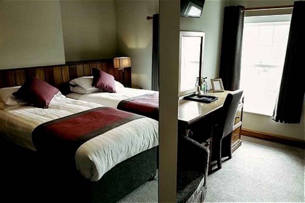 A hotel room with a bed, a desk, a chair, a television, and a window.
