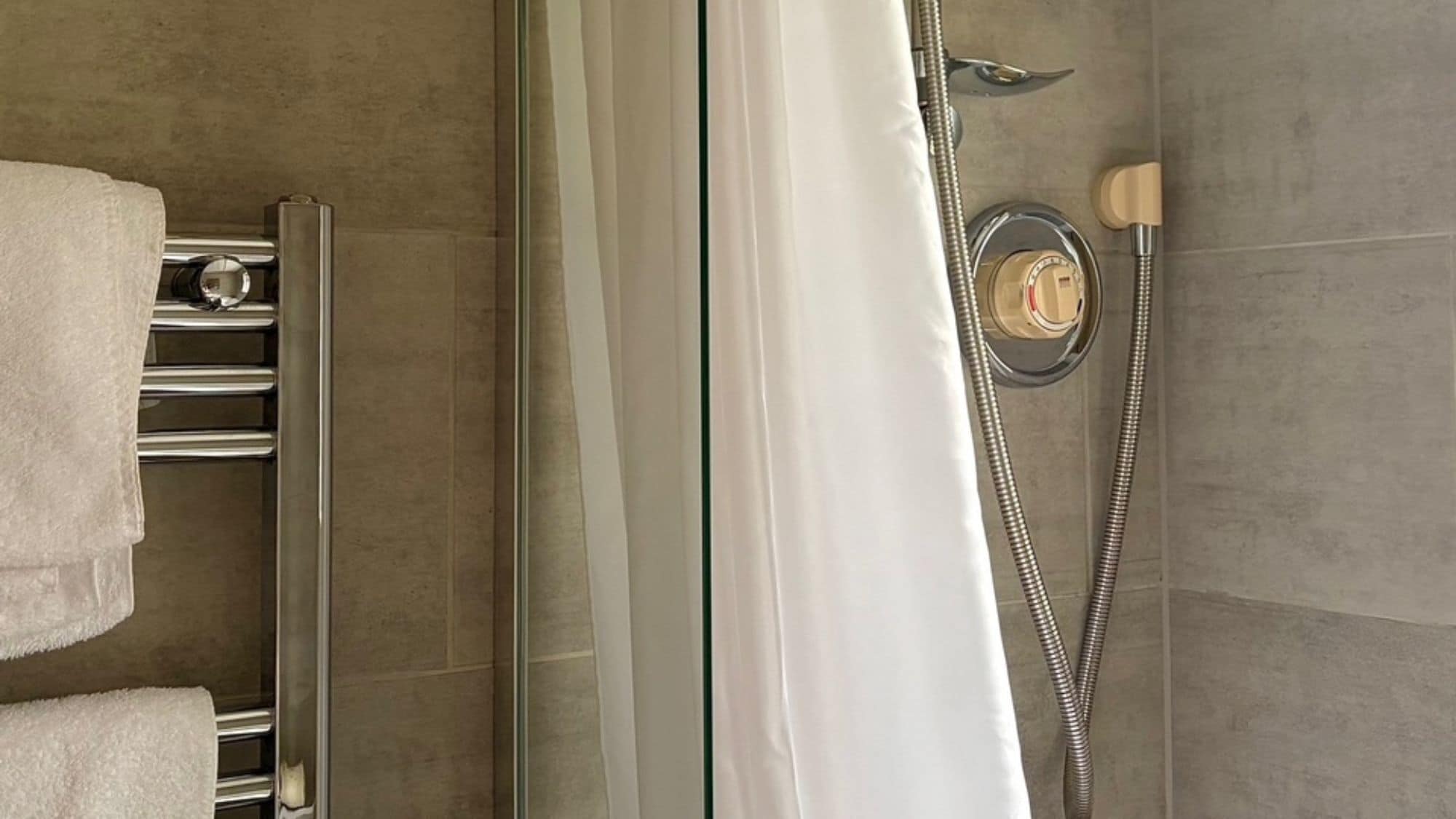 Un angolo doccia con porta in vetro, porta asciugamani e soffione.