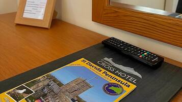 A hotel brochure, a remote control, and a framed sign on a wooden table.