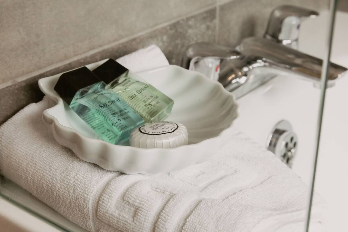A bathroom sink with a white basin, a towel, and two bottles of Sea Spray body spray.