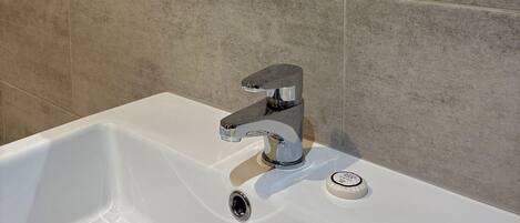 A white bathroom sink with a chrome faucet and a soap dispenser.
