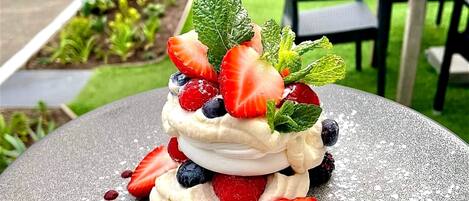 A dessert on a plate with strawberries, blueberries, and mint leaves.