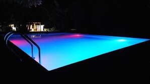 Ein Schwimmbecken mit blauer und pinker Beleuchtung im Dunkeln.