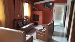 A living room with a sofa, armchair, and a fireplace. - El Aguacate (Baños de Agua Santa)