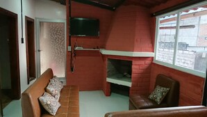 A cozy living room with a fireplace, a sofa, and a television mounted on the wall. - El Aguacate (Baños de Agua Santa)