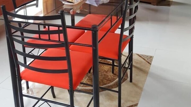 A dining area with a glass table and red chairs, a sofa, and a fireplace. - El Aguacate (Baños de Agua Santa)