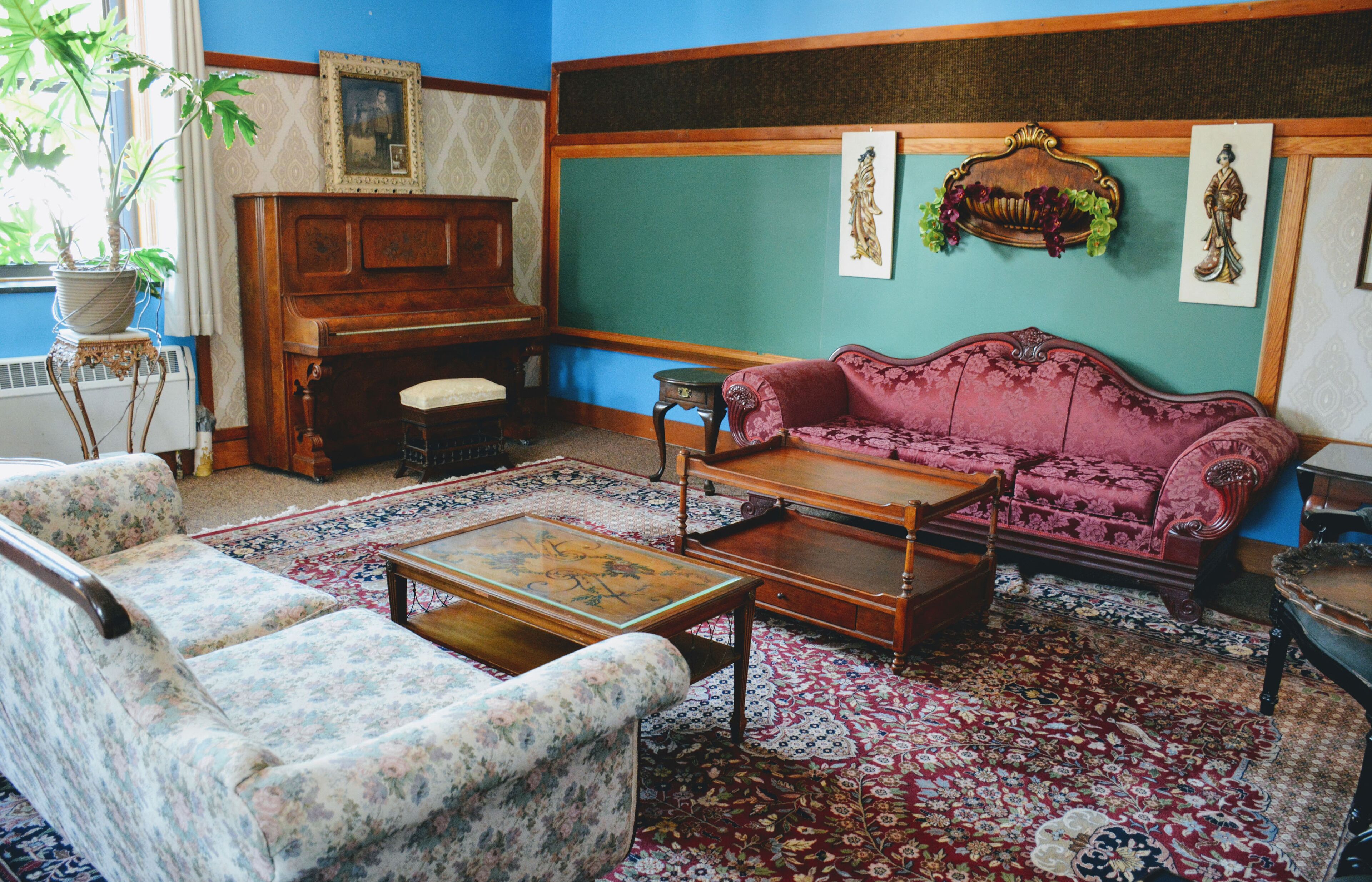 A traditional living room with a floral sofa, a wooden coffee table, and a red patterned rug.