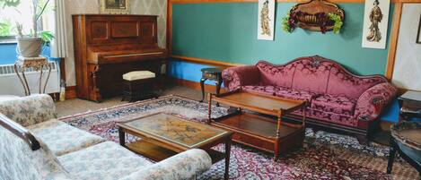 A traditional living room with a floral sofa, a wooden coffee table, and a red patterned rug.
