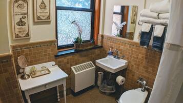 A bathroom with a white sink, a toilet, a mirror, and a window with a view of trees.