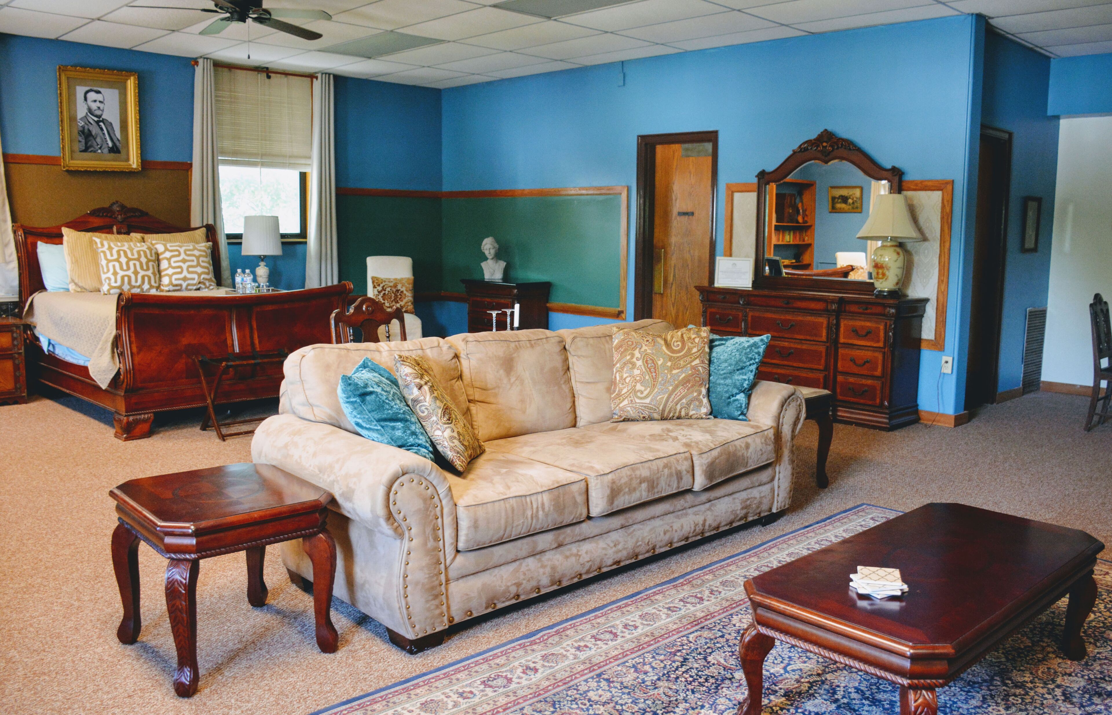 A hotel room with a large bed, a sofa, a coffee table, and a dresser.