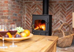 Cozy gathering space with a warm fireplace, wooden table, and wicker basket.