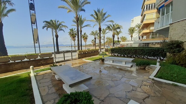 A courtyard with a stone floor, benches, palm trees, and a view of the sea. - Sunset on the beach, Salou (Tarragona)