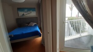 A bedroom with a bed, a painting, and a view of the balcony. - Sunset on the beach, Salou (Tarragona)