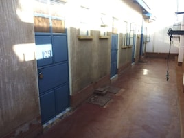Un pasillo con taquillas azules, suelo de baldosas y pared de hormigón.