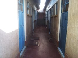 A narrow hallway with blue lockers on both sides and a brown floor.