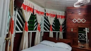 Una habitació amb un llit, un taulell de fusta i cortines amb dibuixos vermells i blancs.