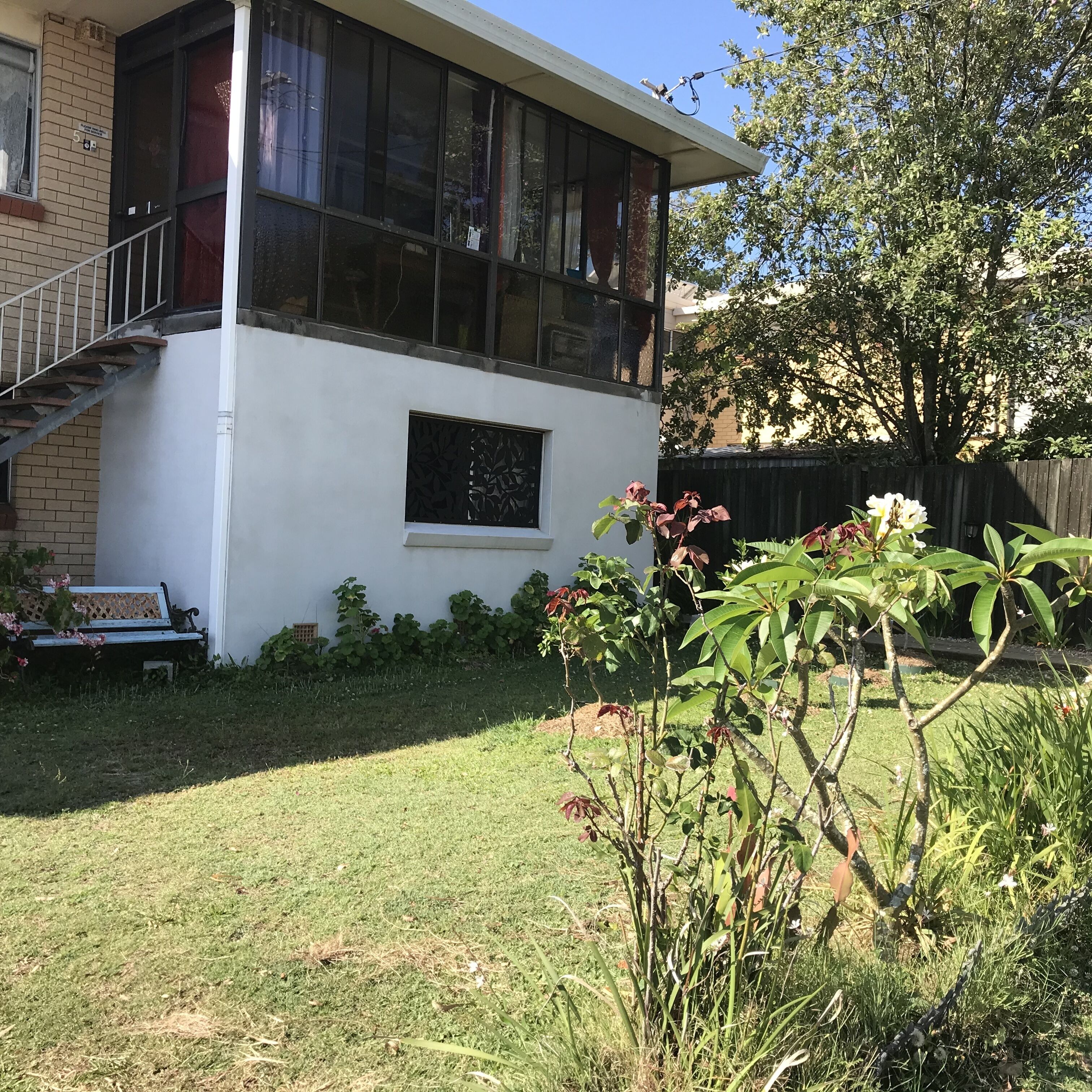 Un edificio de dos pisos con fachada blanca, un ventanal visible y un pequeño balcón.