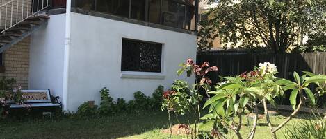 Un edificio de dos pisos con fachada blanca, un ventanal visible y un pequeño balcón.