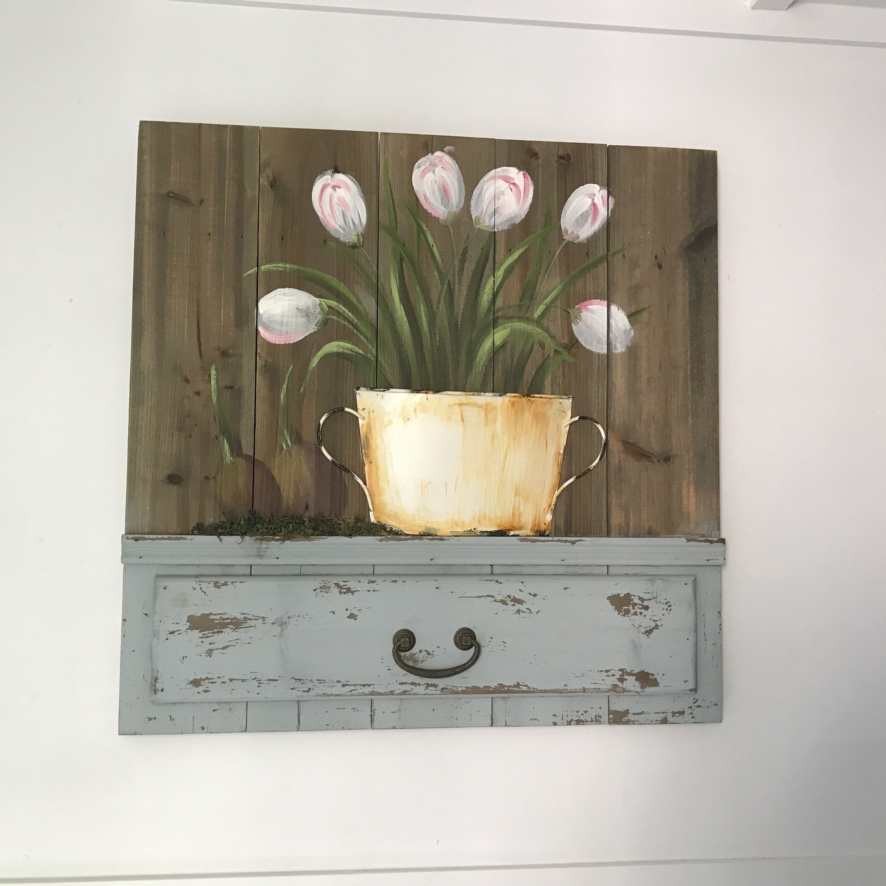 A rustic wall art of a flower pot with tulips.
