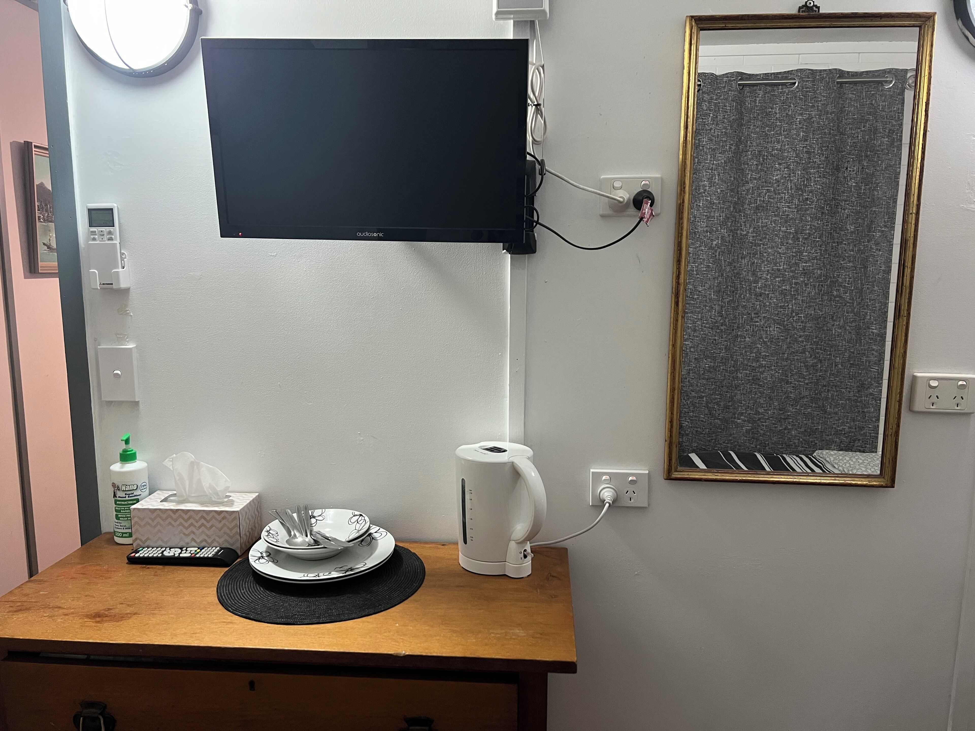 A small kitchenette with a microwave, kettle, and a small table with a plate and utensils.