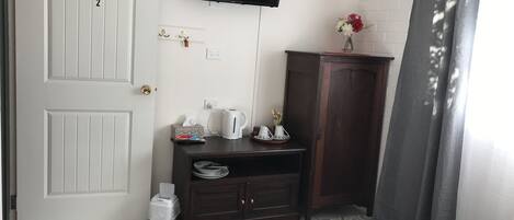 Ein Hotelzimmer mit einem Bett, einem an der Wand befestigten Fernseher, einem Schrank mit Toilettenartikeln und einem gemusterten Teppich.
