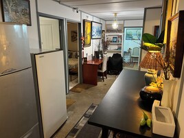 Una cocina compacta con refrigerador, una mesa de comedor con sillas y una pequeña zona de trabajo.