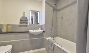 Bañera con ducha, toallas, jabón, shampoo