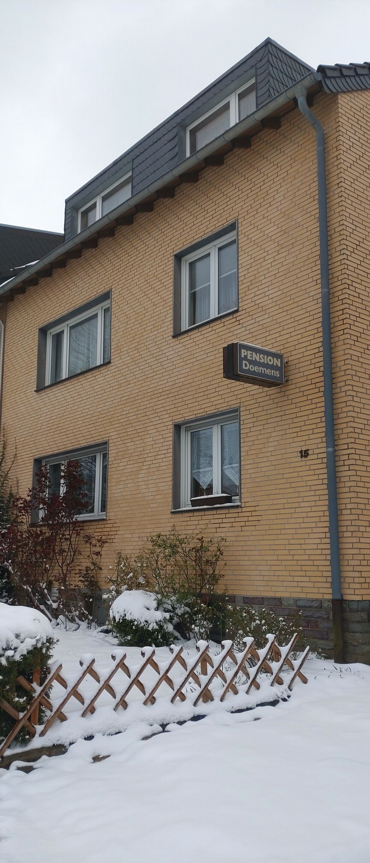 Ein mehrstöckiges Gebäude mit Ziegelaußenwand und einem Schild mit der Aufschrift 'Pension Doemers'.