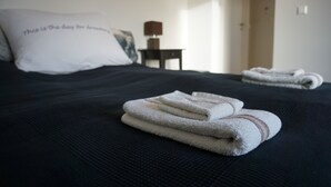 Una cama bien hecha con toallas dobladas y una almohada con texto.
