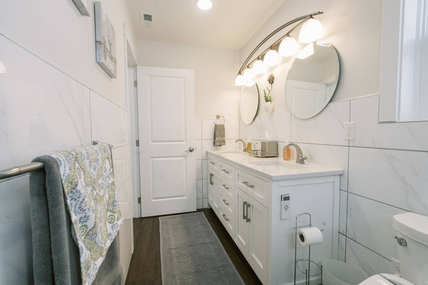 A modern bathroom with a white vanity, a large mirror, and a built-in toilet.