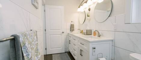 A modern bathroom with a white vanity, a large mirror, and a built-in toilet.