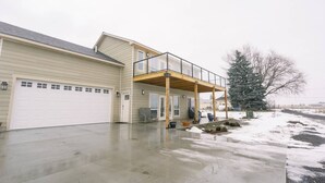 Une maison à deux étages avec un porche abrité, un garage et un paysage enneigé.