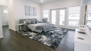 Une chambre à coucher avec un lit, une chaise, un bureau et une grande fenêtre.