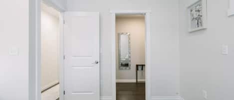A hallway with a white door, a mirror, and a framed picture on the wall.