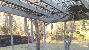 Ein überdachter Patio-Bereich mit Glasverkleidung, einem Metalltisch und einem großen Pflanzgefäß.