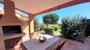 Eine Terrasse im Freien mit einem Backofen aus Ziegeln, einem Tisch mit gestreifter Tischdecke und einem Stuhl.
