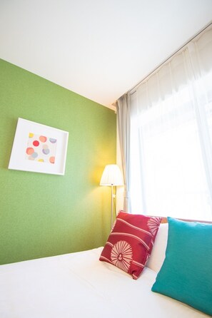 A hotel room with a green wall, a framed picture, a lamp, and a bed with two pillows. - Apartment Hotel Tenjin TUMUGU 302 / Fukuoka Fukuoka (Fukuoka)