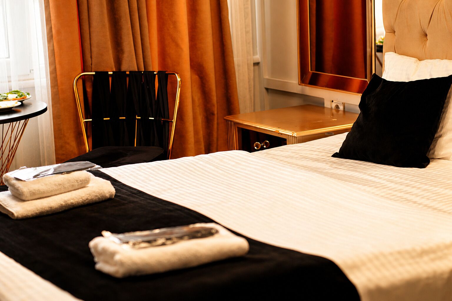 A hotel room with a bed, a chair, a table, and a window with curtains.