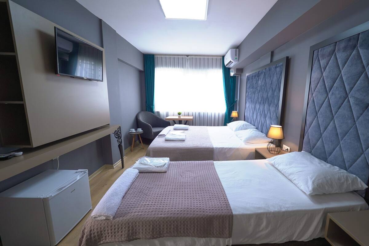 Een hotelkamer met twee bedden, een bureau, een stoel, een televisie en een airconditioning.
