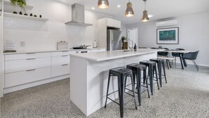 Une cuisine moderne dotée d’un îlot central, de tabourets de bar et de luminaires suspendus.
