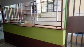 A counter with a green and brown color scheme, a tiled floor, and a window with metal bars. - Silverstone Park Bar & Guest House (Nairobi)