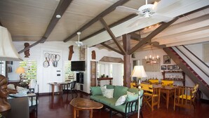 A spacious living room with a green sofa, wooden coffee table, and a dining area with yellow chairs. - Beachcliff Villa Negril (Negril)